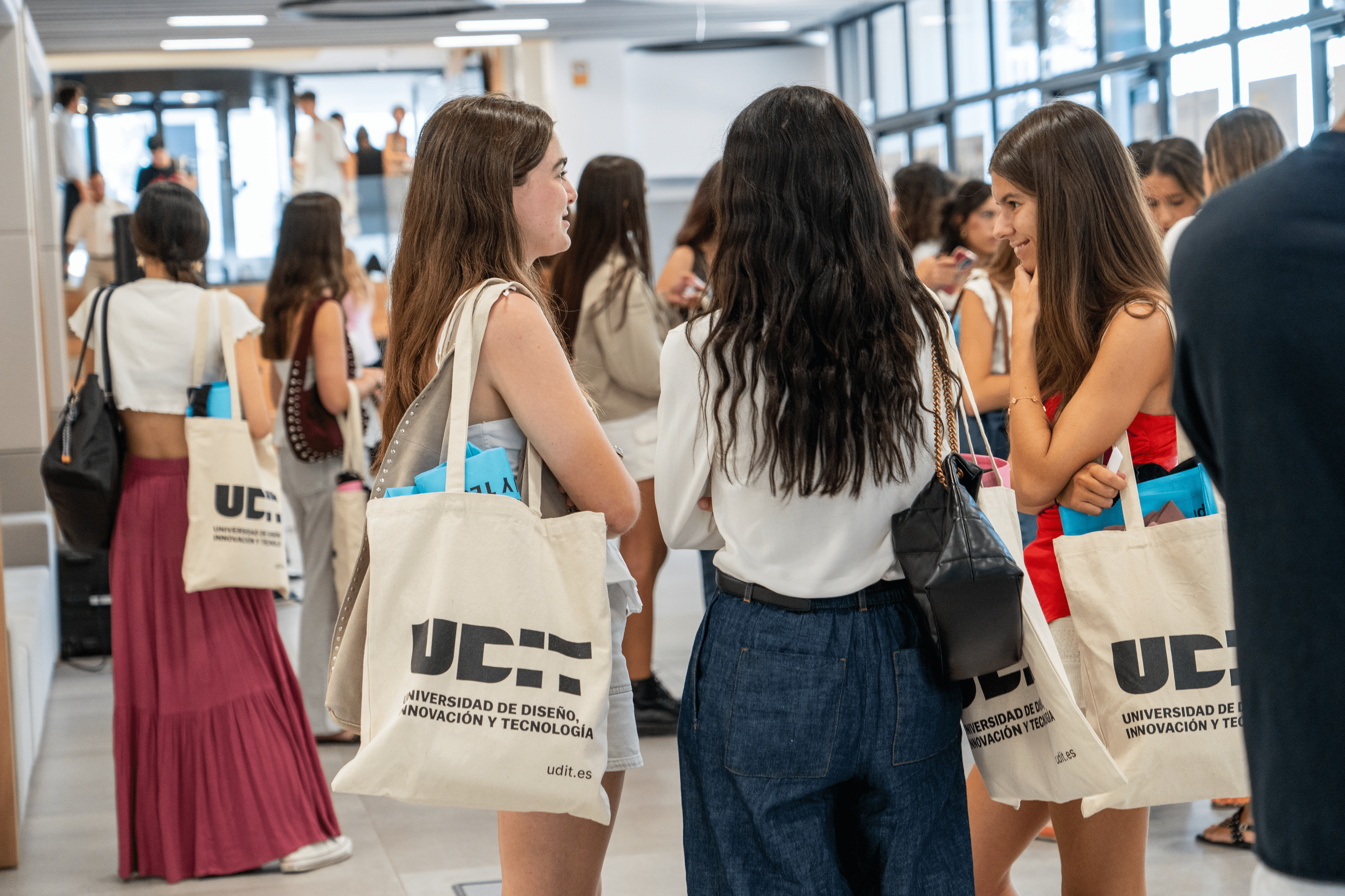 Un grupo de jóvenes con bolsas de la universidad conversan en un ambiente académico.