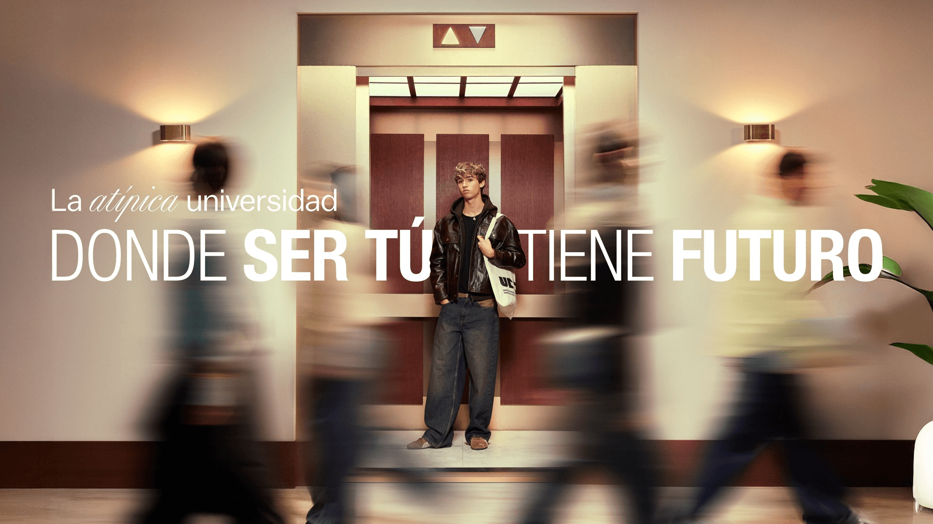 Una persona se encuentra en un entorno universitario con un ascensor de fondo, mientras que otras figuras se mueven en la escena.