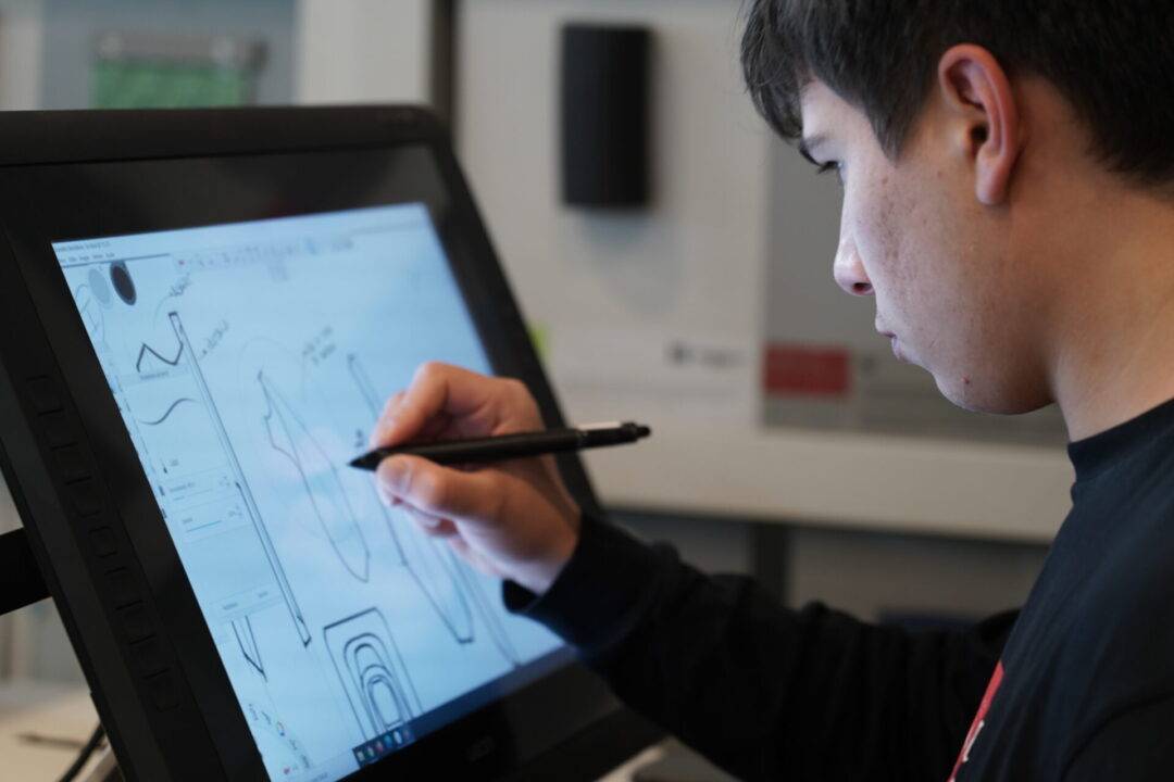 Un joven está dibujando en una tableta gráfica CINTIQ con un lápiz digital.