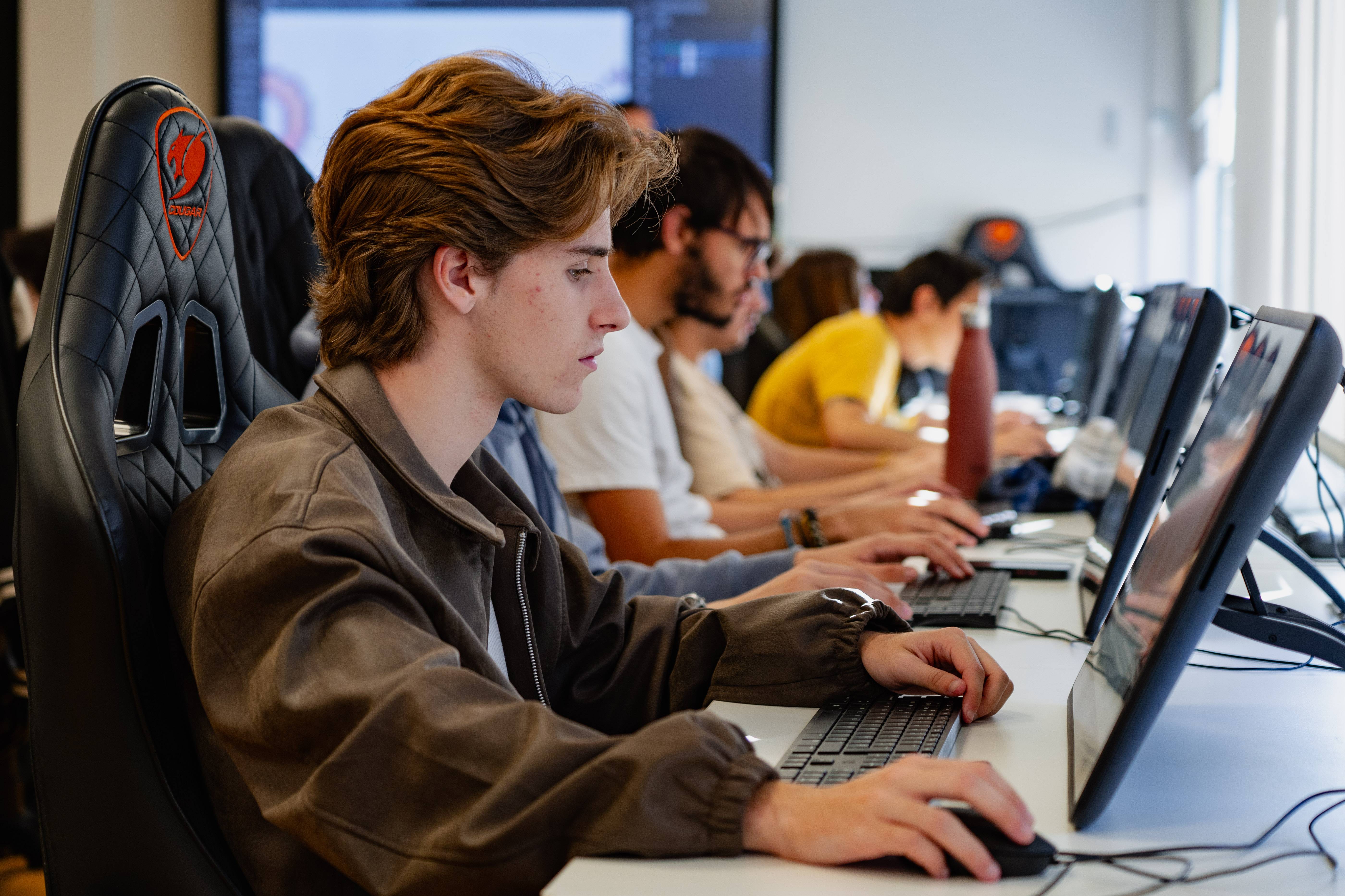 Un grupo de jóvenes trabajando en computadoras en un ambiente colaborativo.