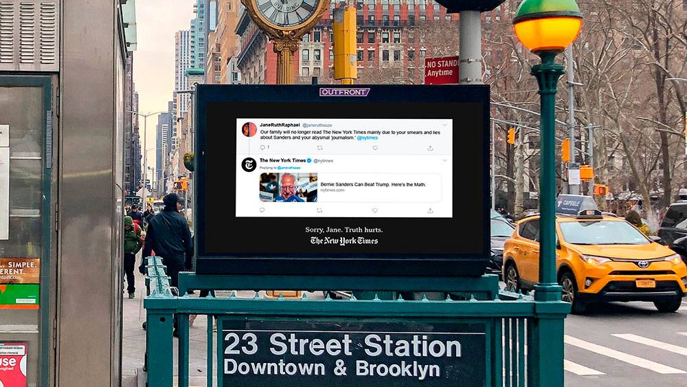 Una imagen de una estación de metro con un anuncio digital y señalización en la calle.