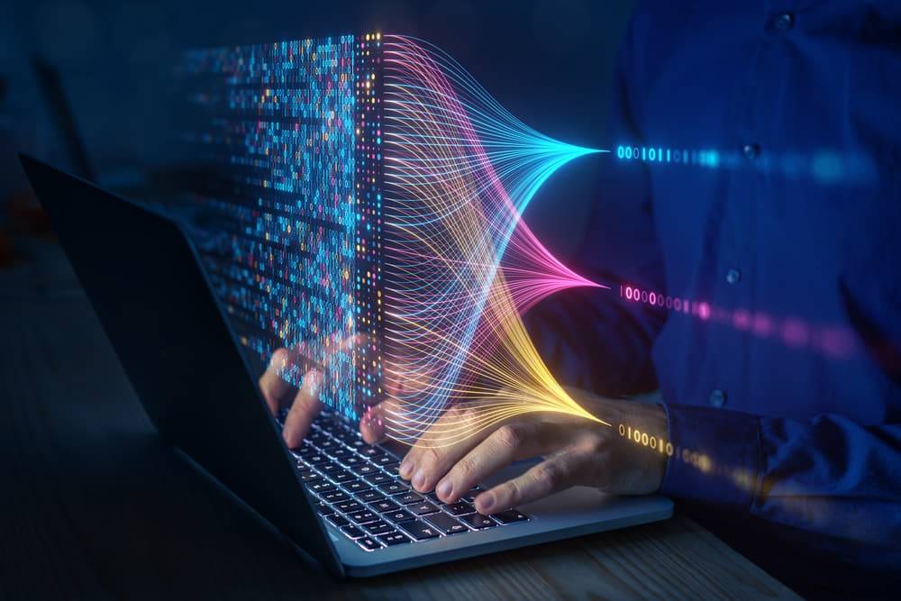 Una persona usa una computadora portátil mientras datos digitales fluyen a su alrededor.