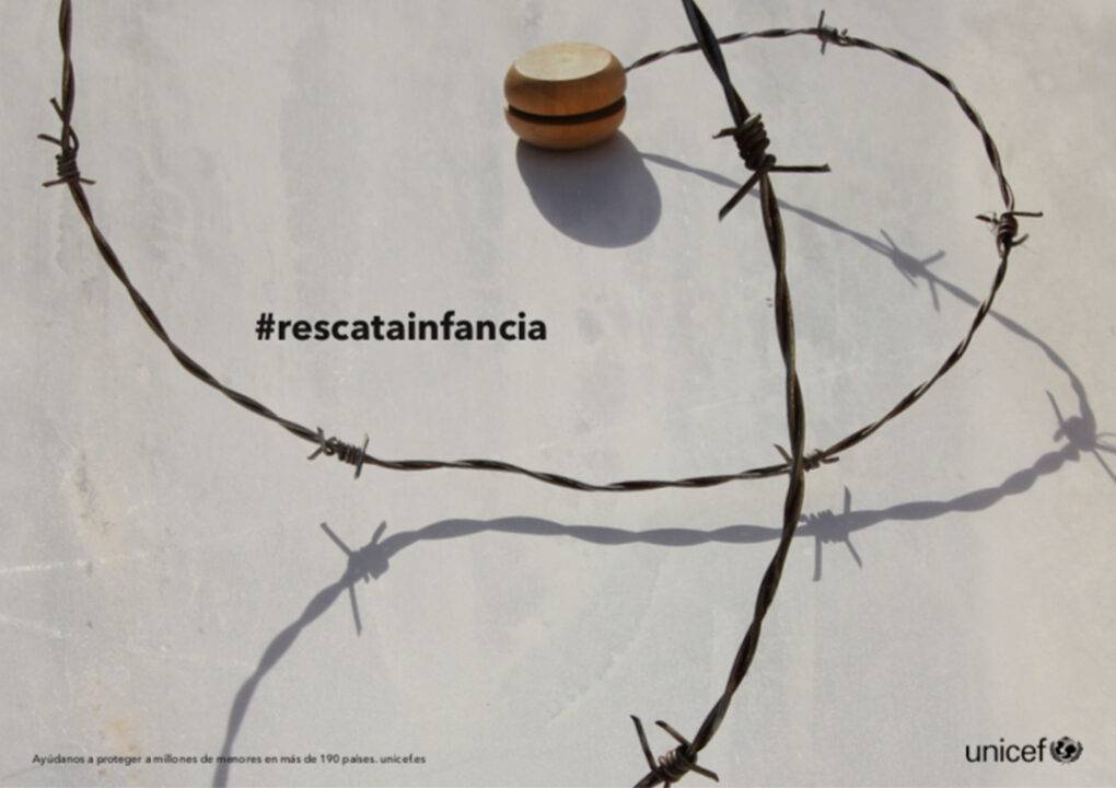 La imagen muestra un objeto de madera en forma de esfera sobre un fondo claro, con alambre de púas formando un patrón alrededor.