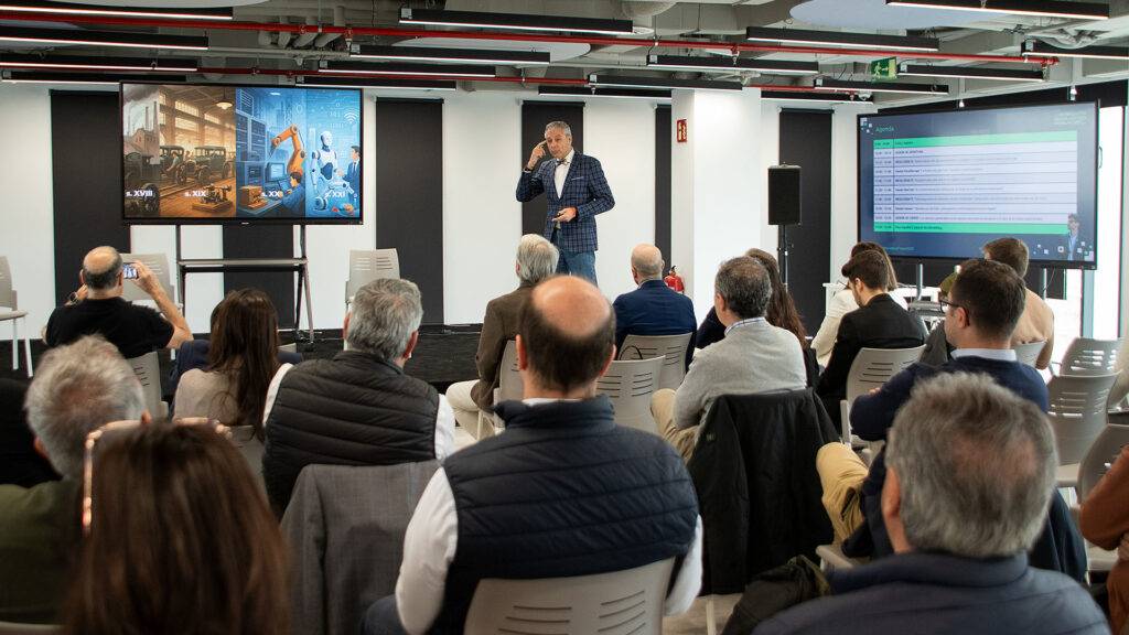 Un ponente presenta un tema frente a una audiencia en un espacio moderno de conferencias.