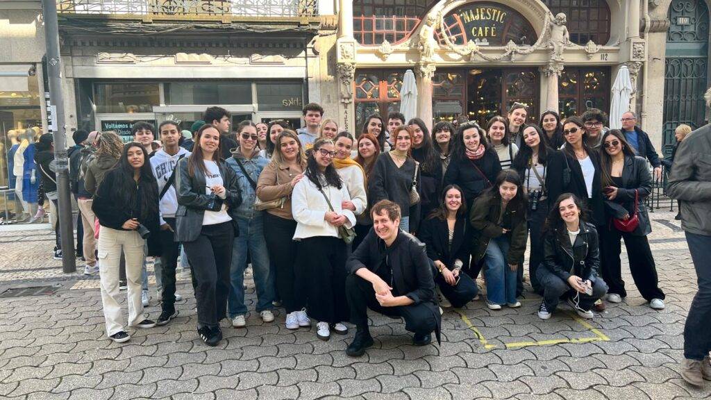 Un grupo grande de personas posando juntas frente a un café en una calle concurrida.