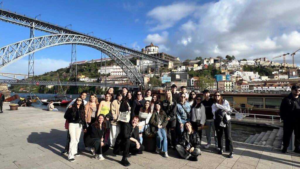 Grupo de personas posando frente a un puente y una ciudad pintoresca.