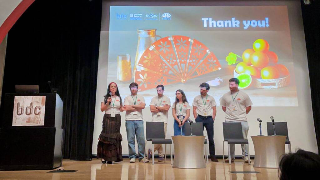 Un grupo de personas en un escenario durante una presentación agradeciendo al público.