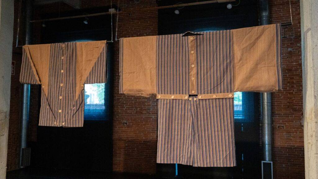 La imagen muestra dos camisones de rayas colgados en un espacio con paredes de ladrillo expuesto.