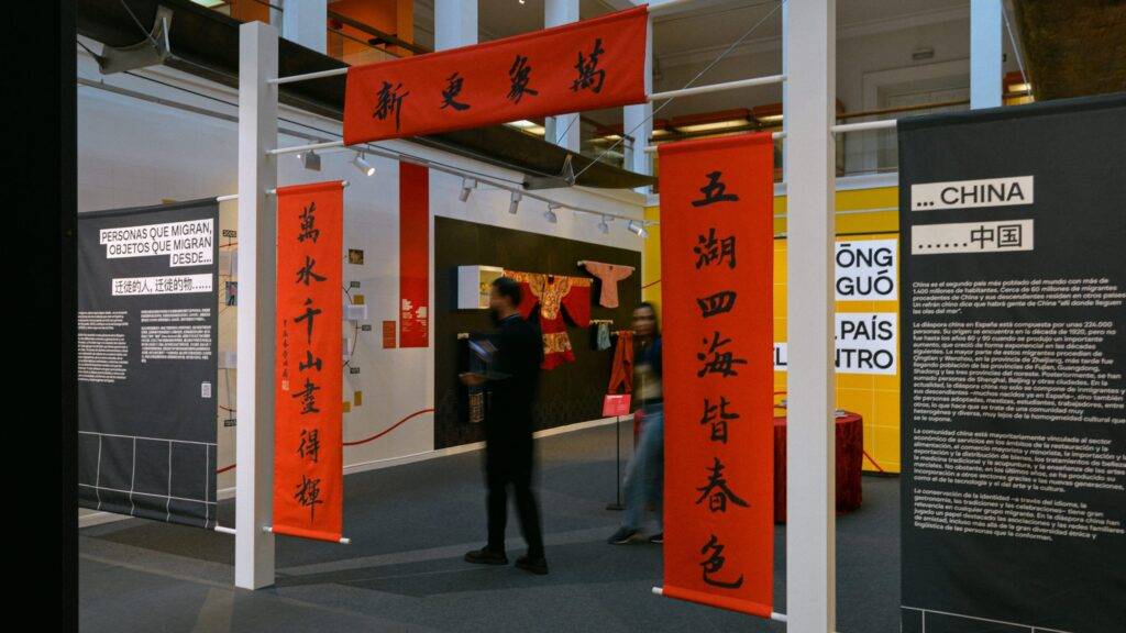Imagen de una exposición con paneles rojos y texto en chino, que muestra el ambiente artístico del evento.