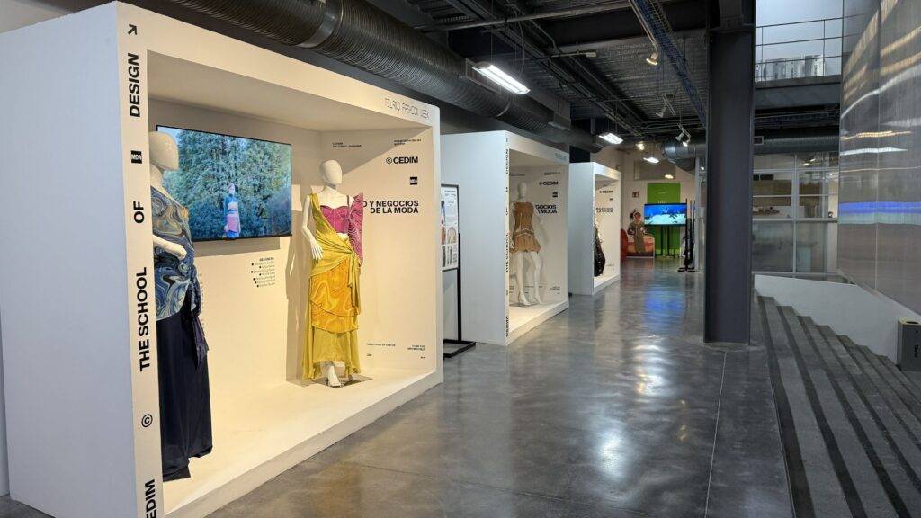 Una exposición de moda con modelos vestidos en diferentes estilos y pantallas interactivas en un ambiente moderno.