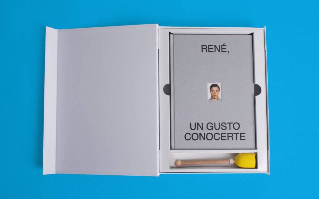 Un libro en una caja blanca que tiene el título 'RENÉ, UN GUSTO CONOCERTE' y una foto en la portada.