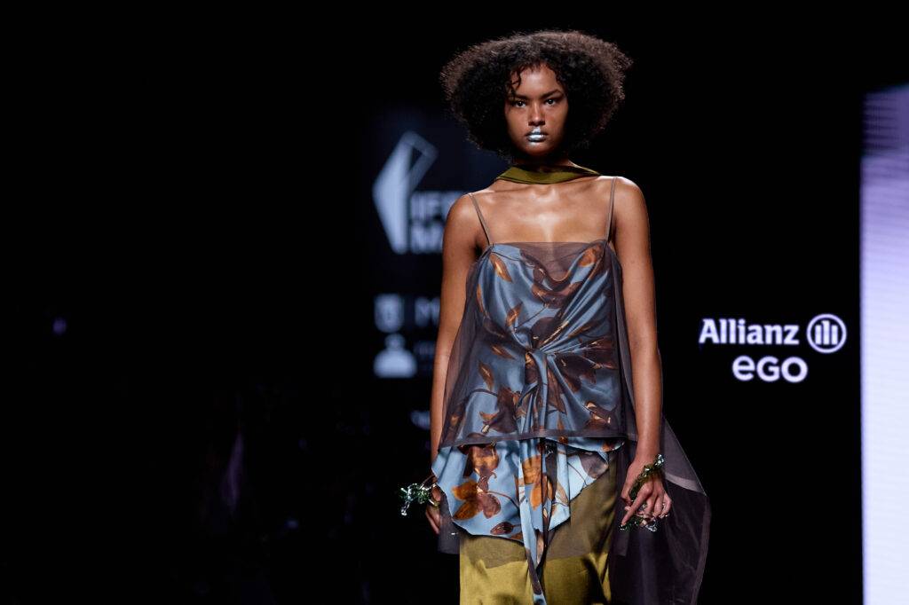 Modelo desfilando con un atuendo moderno y colorido en una pasarela de moda.