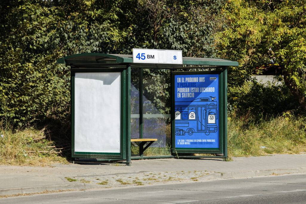 Una parada de autobús con un cartel y un banco vacíos en un entorno natural.