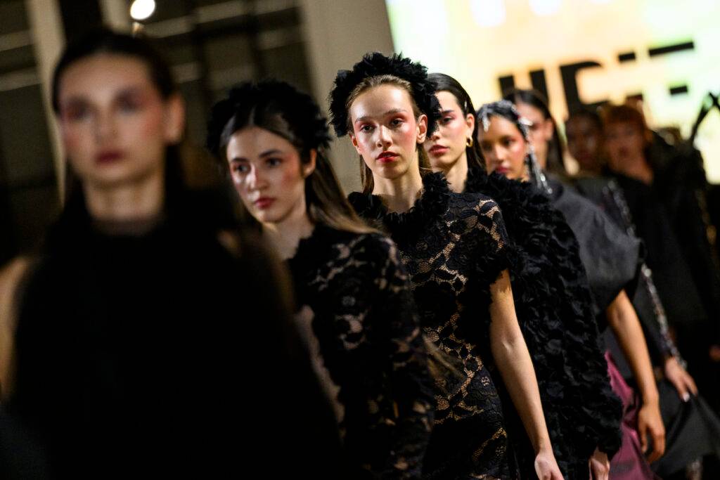 Un grupo de modelos camina en una pasarela luciendo elegantes atuendos de moda.