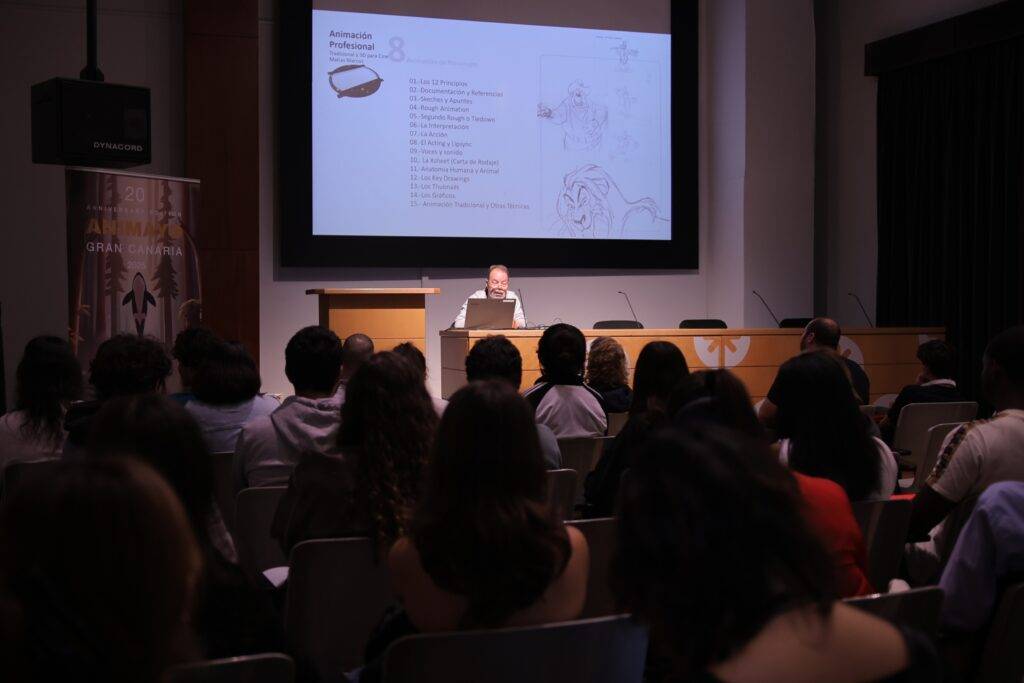 Una persona presenta información en una conferencia ante un público atento.