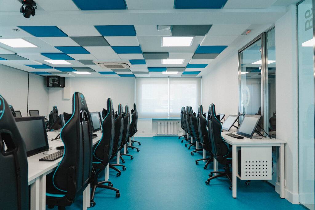 Una aula de computación moderna con escritorios y sillas ergonómicas.