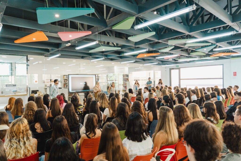 Una audiencia numerosa observa una presentación en una sala moderna.