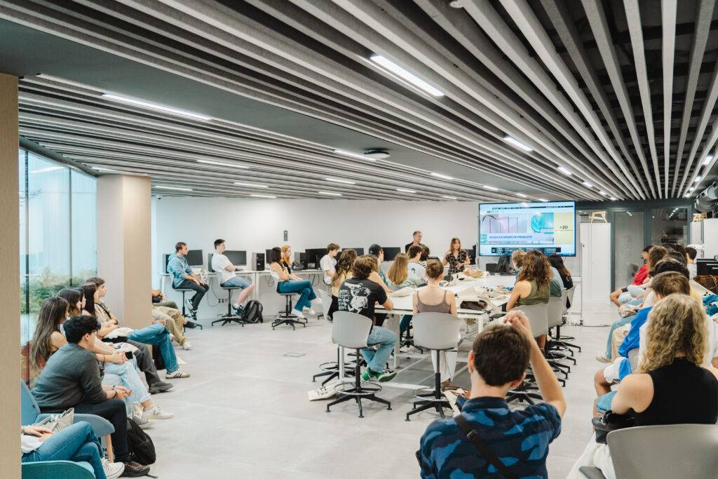 Un grupo de estudiantes se encuentra en un aula moderna durante una presentación en grupo.