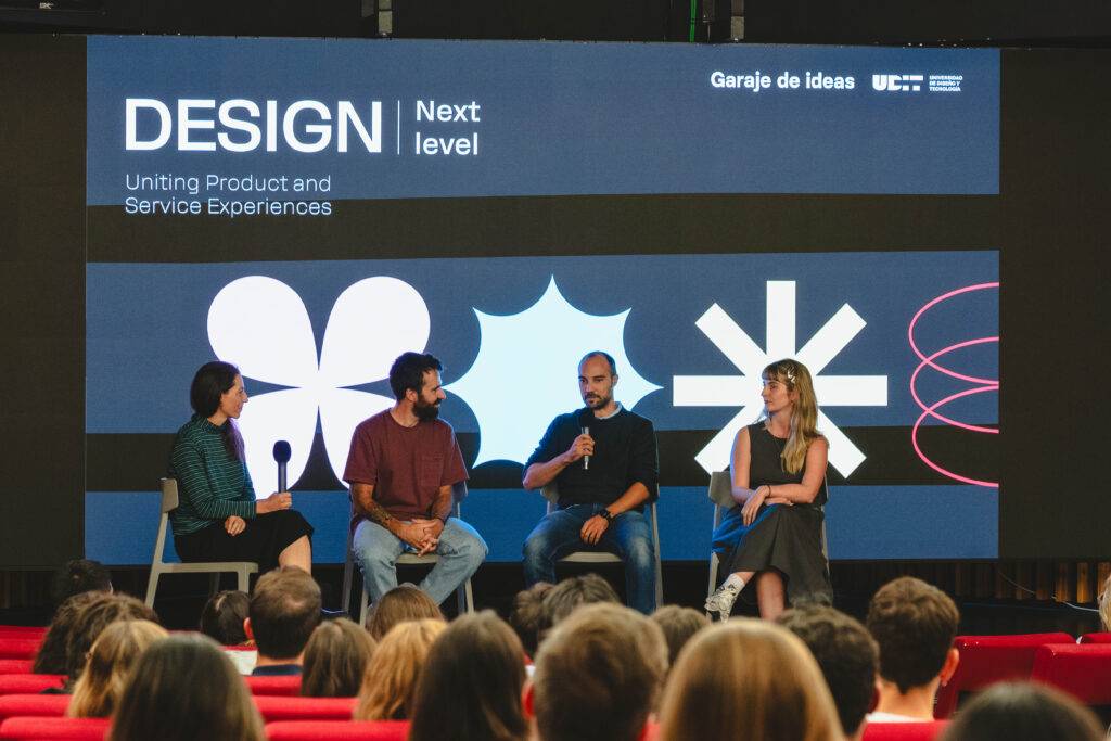 Un panel de discusión sobre diseño, con cuatro personas sentadas frente a una audiencia en un ambiente moderno.