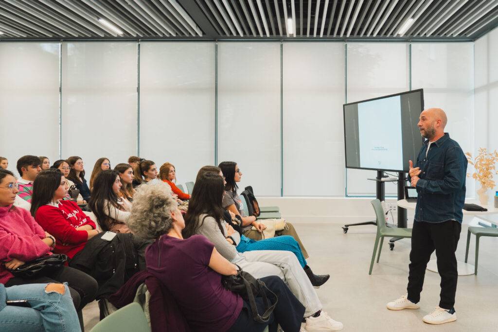 Una persona está dando una charla frente a un grupo de estudiantes en un aula moderna.