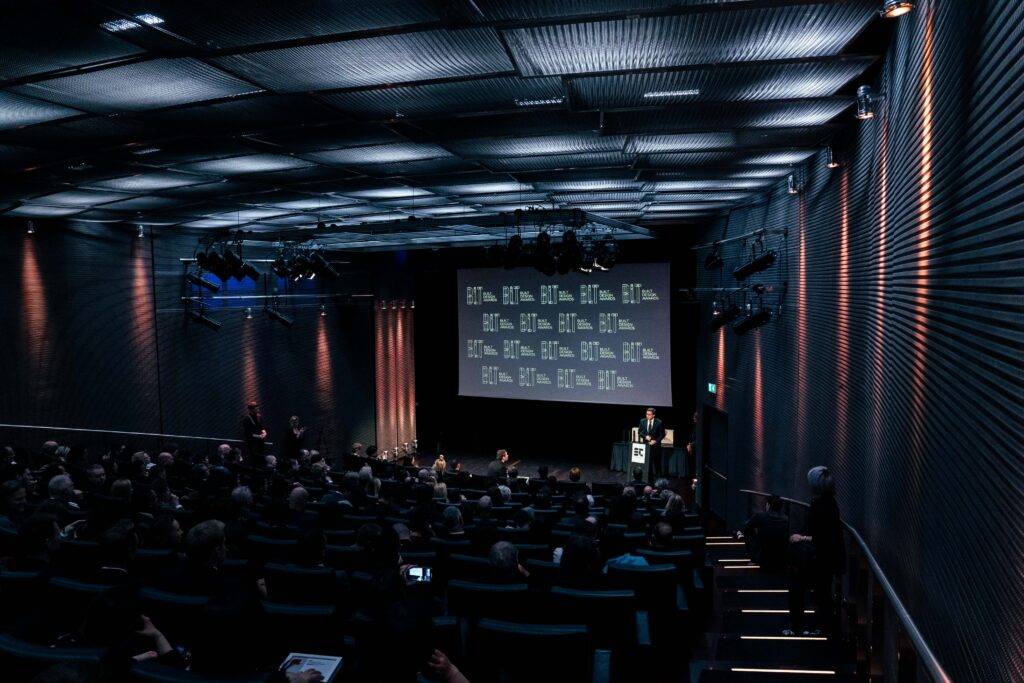 Una sala de conferencia con un gran público asistiendo a una presentación.