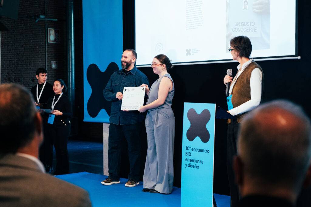 Un grupo de personas en un escenario durante un evento de diseño, recibiendo un reconocimiento.
