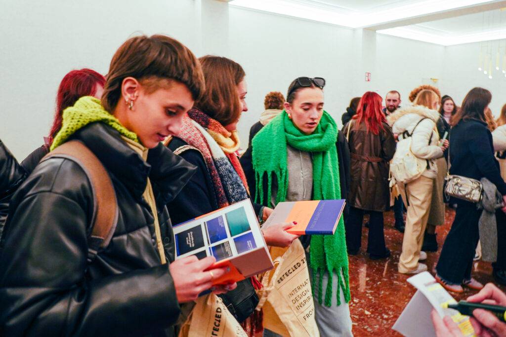 Un grupo de personas en una sala, algunas de ellas sosteniendo libros y con atuendos coloridos.