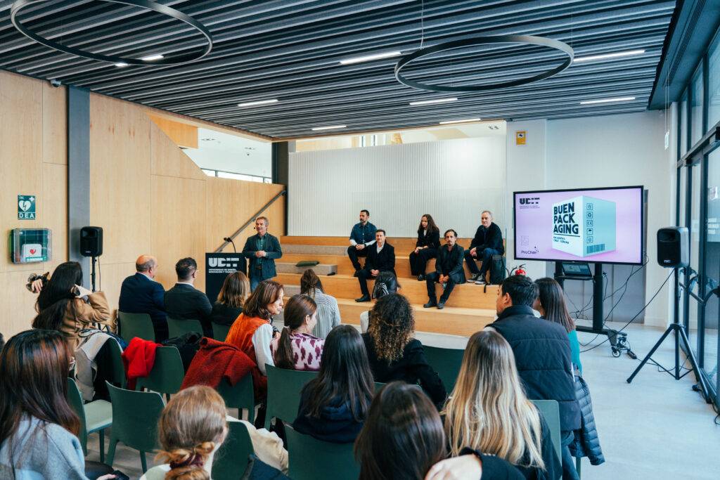 Un evento en un auditorio donde varias personas están en un panel discutiendo sobre el empaque sostenible.