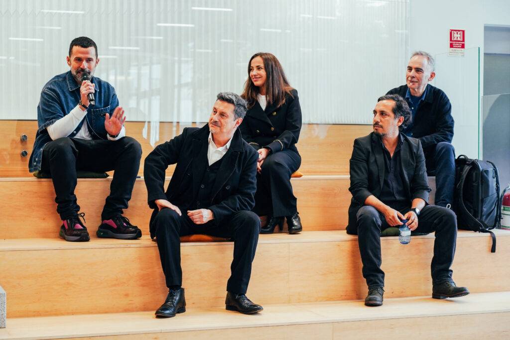 Un grupo de cinco personas sentadas en un escenario realizando una charla o presentación.