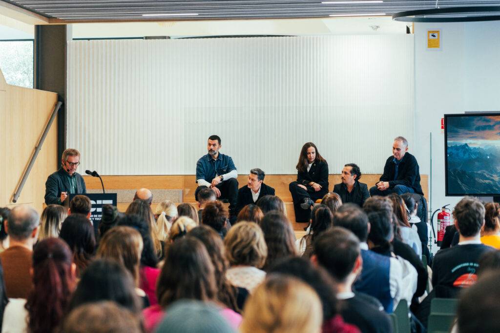 Un grupo de personas en un panel discutiendo frente a una audiencia en un evento.