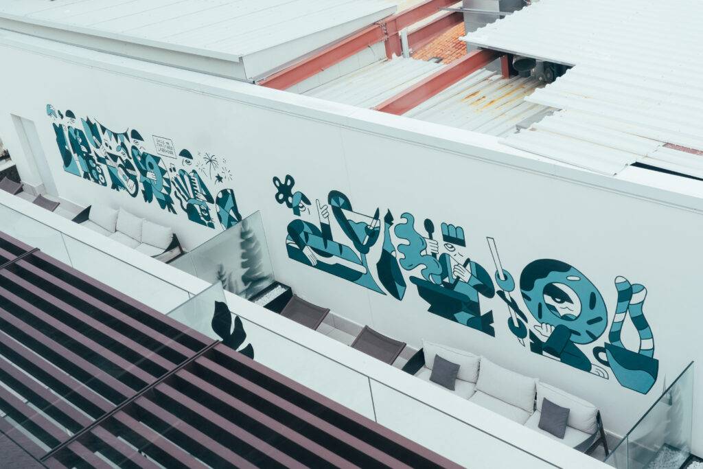 Una mural colorido adornando una pared exterior con figuras estilizadas y abstractas.