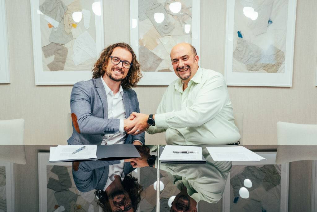 Dos hombres se dan la mano en un ambiente profesional, mostrando un acuerdo o cooperación.