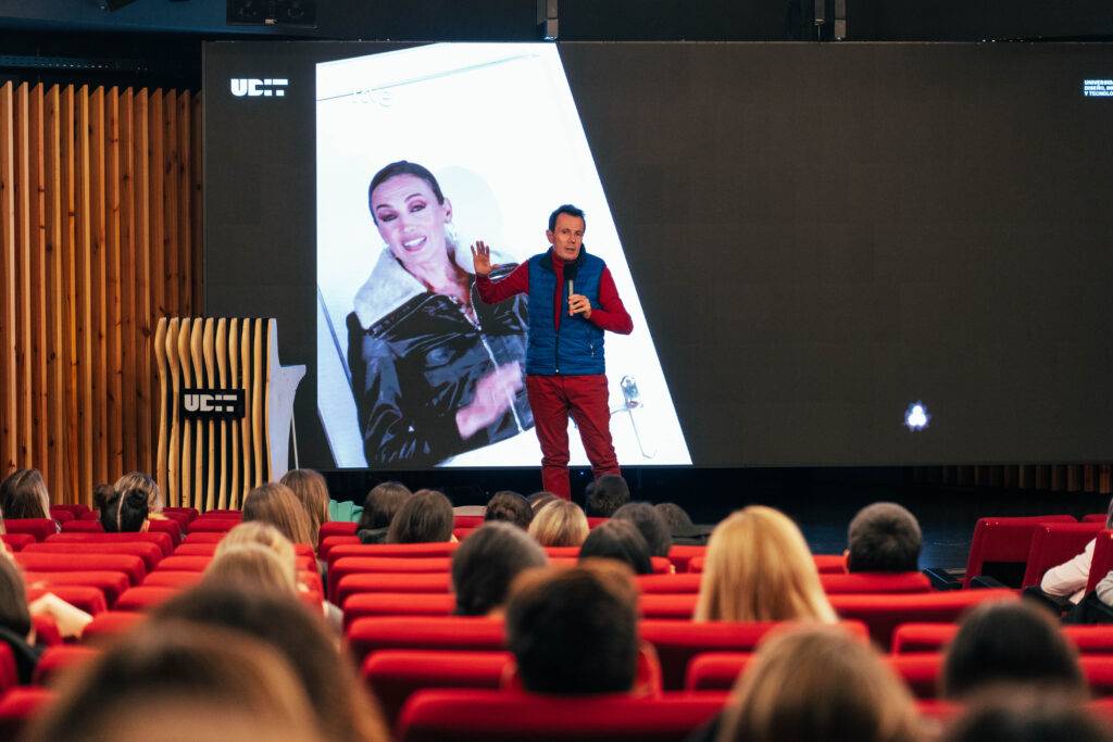 Un orador presenta frente a una audiencia mientras se proyecta una imagen en una pantalla grande.