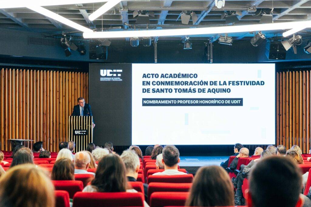Un acto académico en honor a la festividad de Santo Tomás de Aquino, con un ponente en un auditorio lleno de personas.