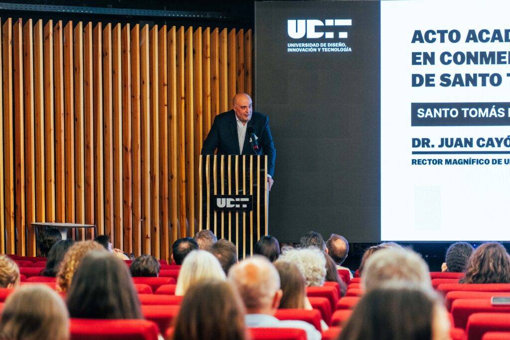 Un acto académico en la Universidad de Diseño Innovación y Tecnología con un ponente frente a la audiencia.