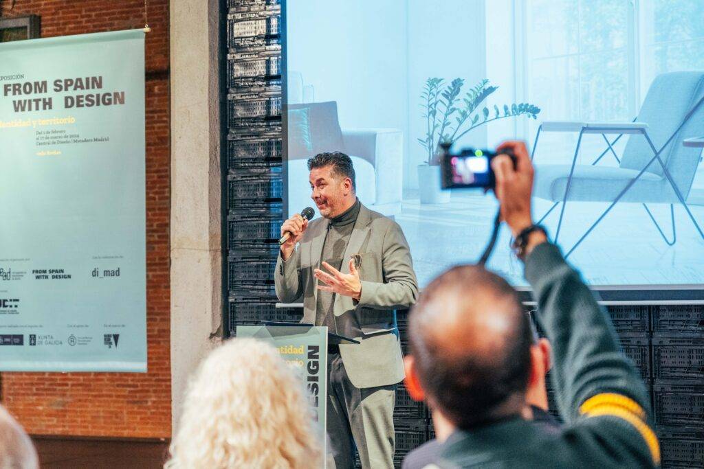Un hombre habla en un evento de diseño mientras otra persona lo fotografía.