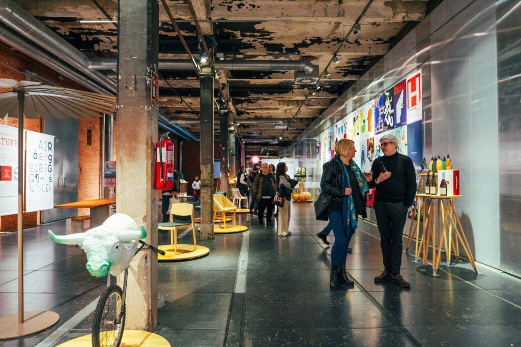 Una exposición con personas conversando en un espacio moderno con instalaciones artísticas.