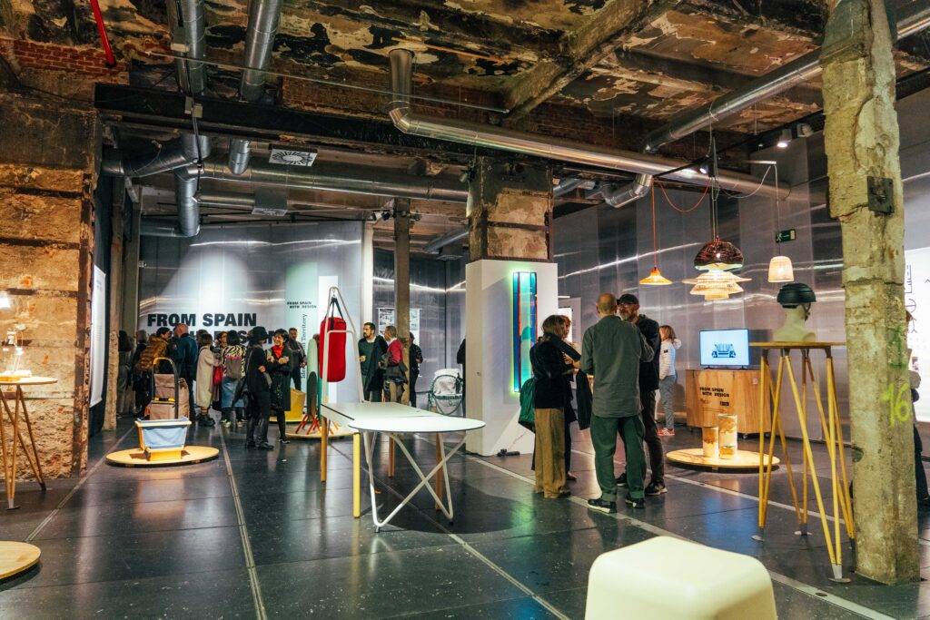 Una exposición de diseño con varias personas interaccionando en un espacio moderno.