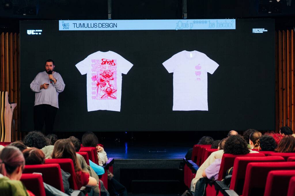 Un presentador muestra camisetas con diseños gráficos en una conferencia.