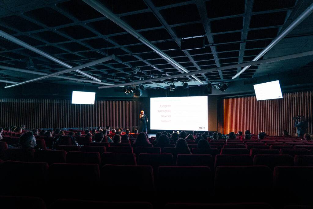 Una conferencia con un orador frente a una audiencia en un auditorio.