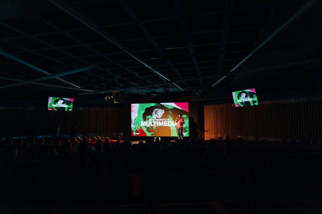 Una sala de conferencias con una presentación multimedia proyectada en pantallas.