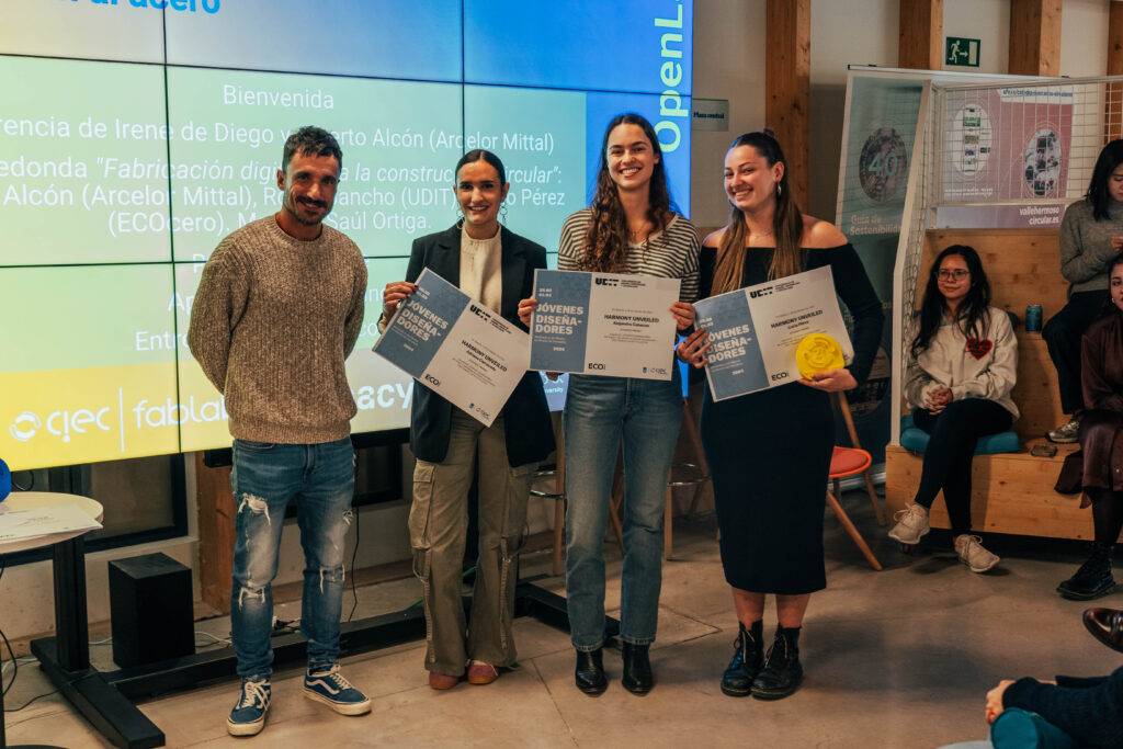 Un grupo de cuatro personas sostiene certificados en un evento de premiación.