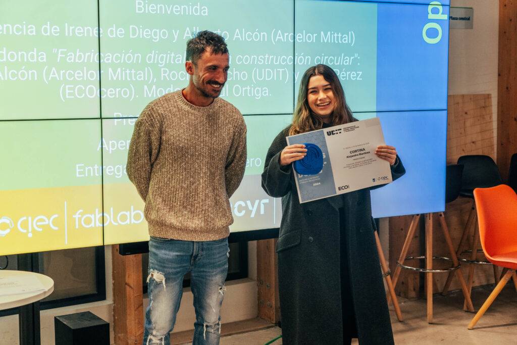 Un evento de entrega de certificados con dos personas sonriendo, una sosteniendo un diploma.