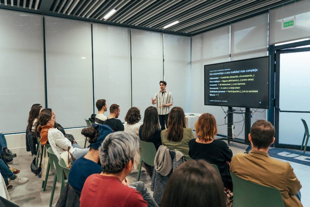 Una persona está dando una presentación frente a un grupo de personas en una sala con proyector.