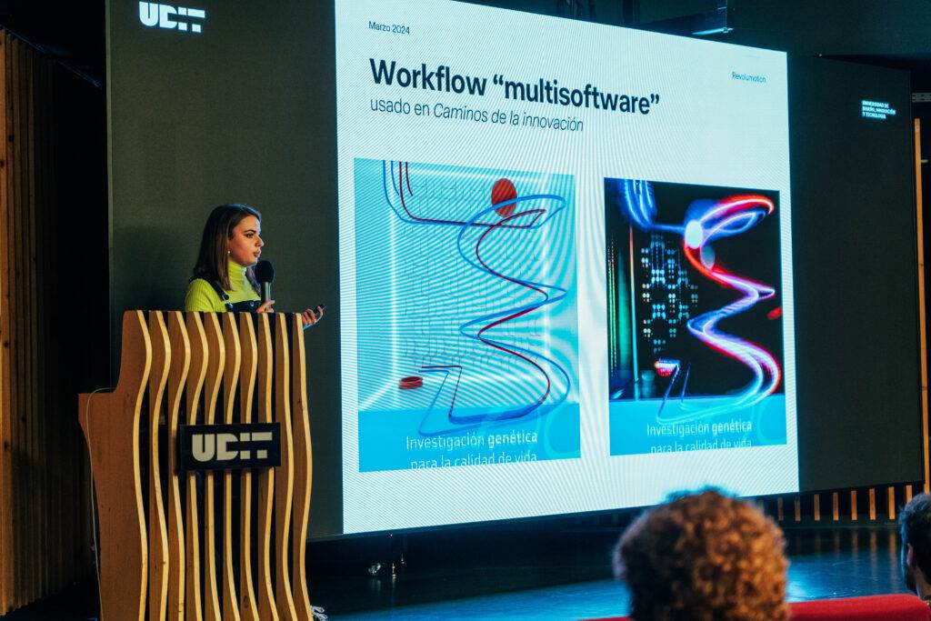 Una presentadora expone sobre un flujo de trabajo 'multisoftware' en una conferencia, con imágenes sobre investigación genética proyectadas detrás de ella.