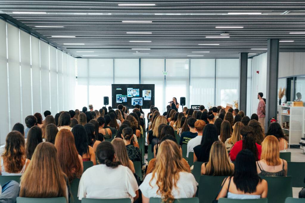 Una multitud de personas sentadas en un salón durante una presentación.