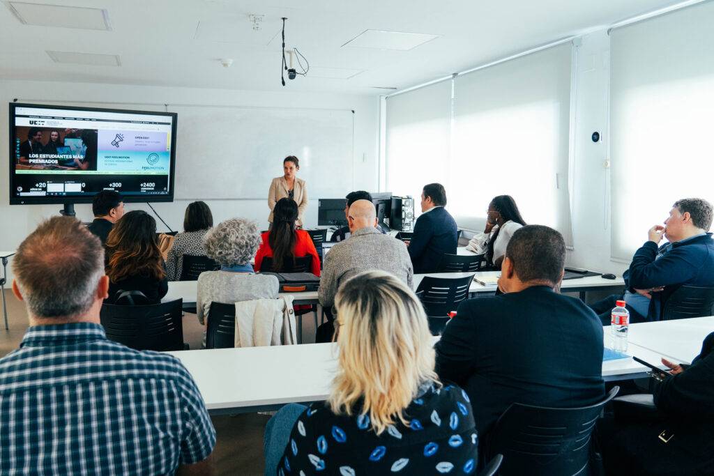 Una persona está dando una presentación frente a un grupo de asistentes en un aula moderna.
