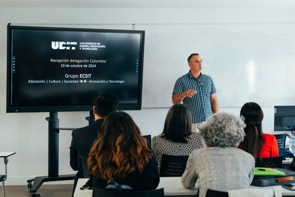 Un profesor presenta un tema relacionado con la educación y la tecnología a un grupo de asistentes en un aula.