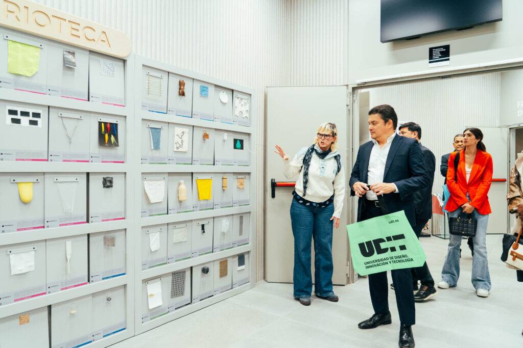 Un grupo de personas explora una exposición de objetos de diseño en una sala moderna.