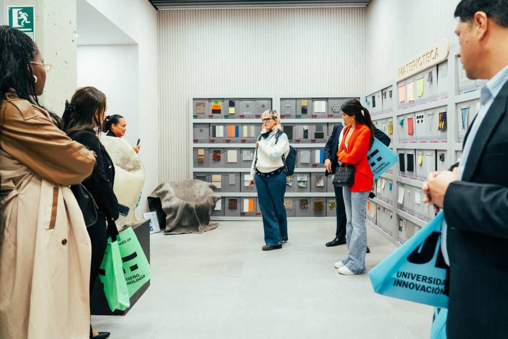 Un grupo de personas observa una presentación en un espacio expositivo moderno.